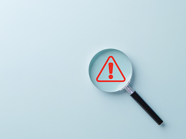 red warning triangle inside magnifying glass
